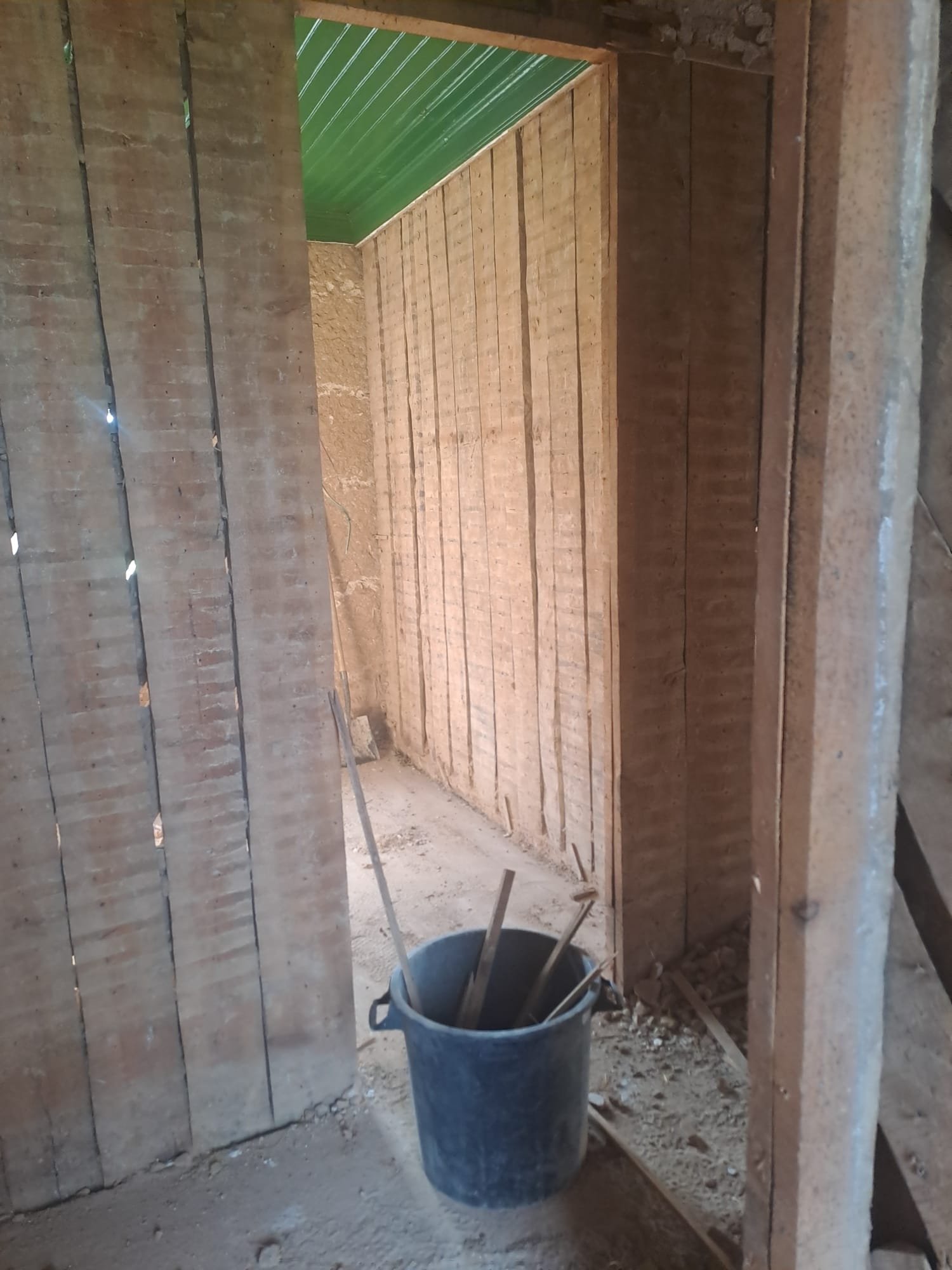 A bucket of pry bars and tools in a stripped-out room