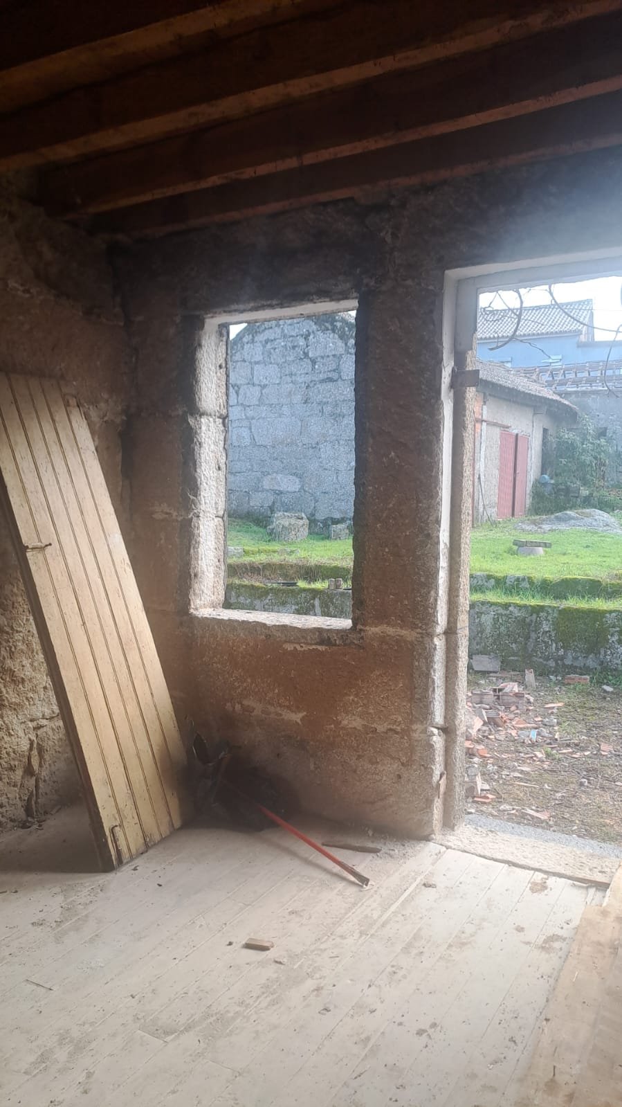 A room mid-strip-out, with an old door leaning against a brick-filled window