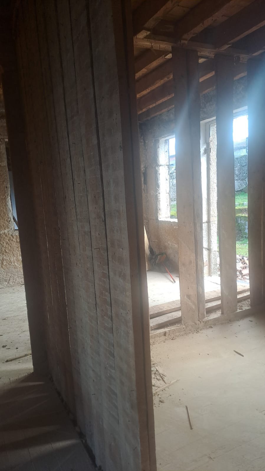 Stripped-back stud wall and window opening inside the house