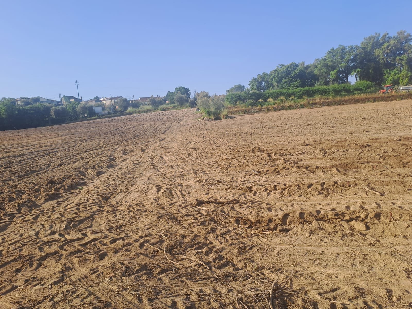 Freshly tilled field with tractor working in the distance, May 2025